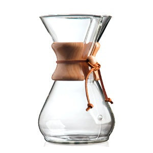A Chemex coffee brewer that is single glass piece in an hour shape with a wooden collar near the top