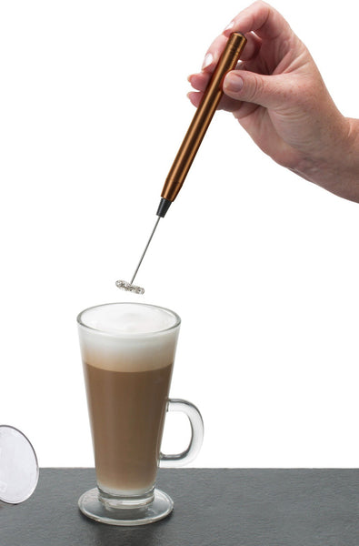 A slimline copper frother whipping milk for a latte drink