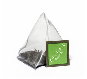 A single prism green tagged tea bag of Birchall Green Tea. Mesh tea bag with large loose leaf inside.