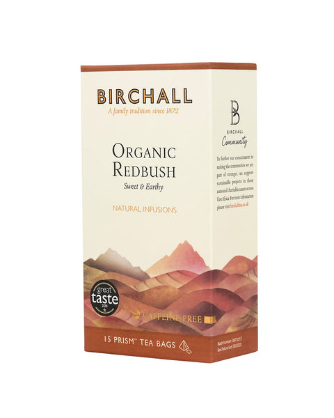 Right side view of cardboard box of 15 Birchall Organic Redbush prism tea bags. Orange hill graphics with orange band, sweet & earthy, natural infusion. Caffeine free. Great Taste winner 2014