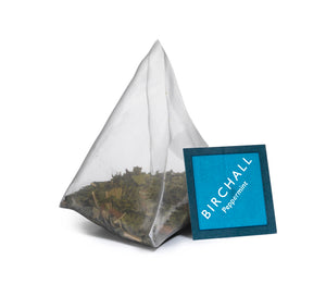 A single prism blue tagged tea bag of Birchall Peppermint tea. Mesh tea bag with large loose leaf inside.