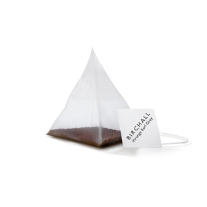 A single prism white tagged tea bag of Birchall Virunga Earl Grey tea. Mesh tea bag with small loose leaf inside.